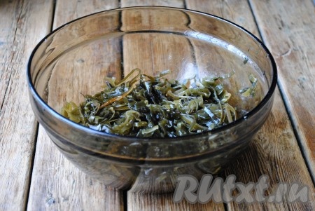 С маринованной морской капусты слить жидкость. Если капуста очень длинная, то её нужно разрезать пополам или на несколько частей. Морскую капусту выложить в глубокую миску. 