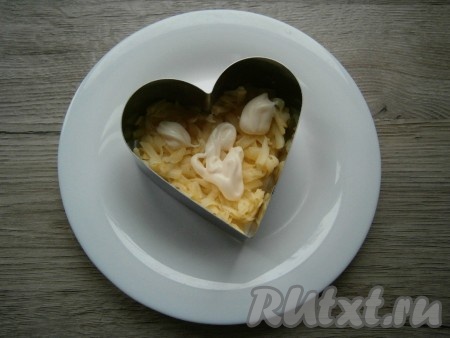 Салат будем формировать на тарелке с помощью кулинарного кольца в виде сердца. Первым слоем выложить очищенный картофель, натертый на крупной терке, посолить немного, смазать майонезом.