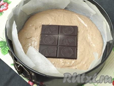 Форму диаметром 22-24 см проложить пергаментом, вылить половину теста. В центр положить плитку шоколада.
