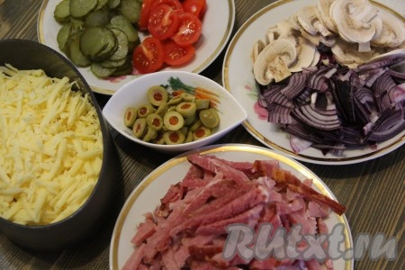 Начинку для пиццу можно сделать, исходя из ваших вкусовых предпочтений. Мясное ассорти (колбасу) нарезать соломкой или кубиками. Свежие шампиньоны нарезать тонкими пластинами. Огурцы, помидоры и оливки нарезать кружками. Очищенный лук нарезать полукольцами. Сыр натереть на тёрке.