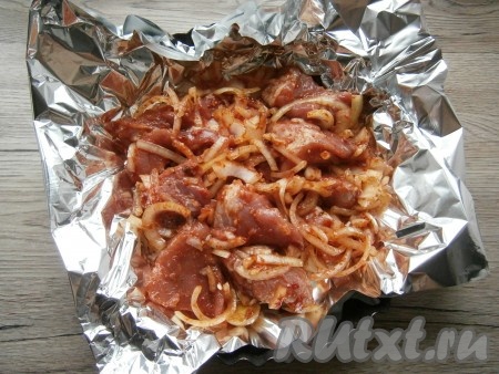 Выложить свинину с луком в фольгу, сбрызнуть несколькими каплями жидкого дыма, края фольги сверху соединить, прикрыв мясо.
