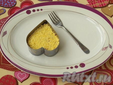 Желток и белок следует натереть по отдельности. Желток выложить сверху овощного слоя, нанести майонез.
