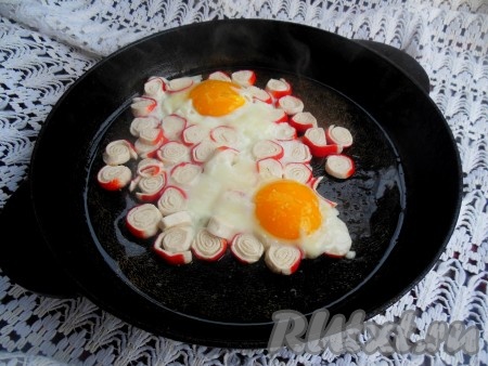 Готовьте яичницу с крабовыми палочками на небольшом огне, примерно, 4 минуты (белок должен "схватиться"). Следите, чтобы крабовые палочки не подгорели. При желании, для того чтобы желток лучше прожарился, можно накрыть сковороду крышкой (я этого не делала). В конце приготовления посолите яичницу по вкусу.
