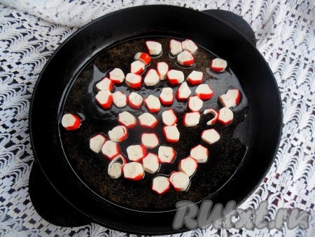 Сковороду разогрейте, добавьте растительное масло, через пару секунд выложите крабовые палочки. Прогрейте крабовые палочки на сковороде на небольшом огне в течение одной минуты, помешивая.
