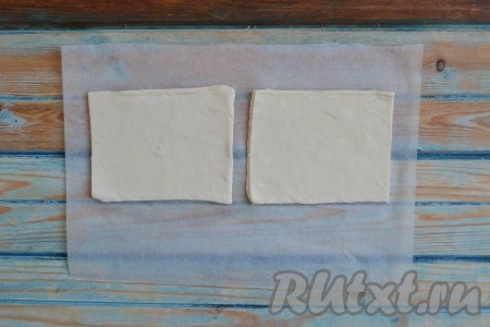 Слоеное тесто оставить размораживаться в холодильнике (лучше на ночь). Если времени мало, то можно разморозить в микроволновке на режиме "Разморозка". Затем тесто необходимо аккуратно размотать и выложить пластом на пергамент или стол, присыпанный мукой. Раскатывать его не нужно. Разрезать тесто на равные квадраты. Размер зависит от ваших предпочтений: чем большее квадрат, тем больше нужно положить начинки и тем больше получится сама слойка. Я разрезала на квадраты 8х8 см.