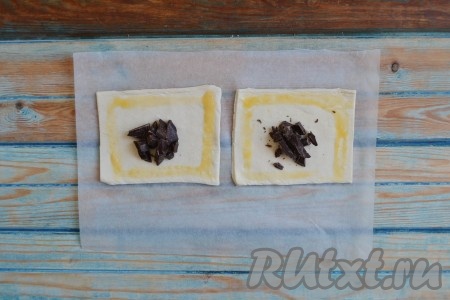 Смочив в яйце кисточку, аккуратно смазать края заготовок (как на фото). Шоколад порубить ножом в мелкую крошку и выложить в центр.
