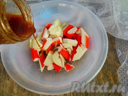 Получившейся смесью залейте нарезанные крабовые палочки, добавьте лук и чеснок.
