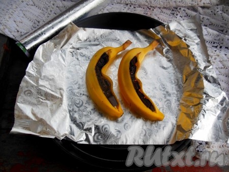 На противень выложите кусок фольги. На фольгу поместите 2 банана с шоколадом.
