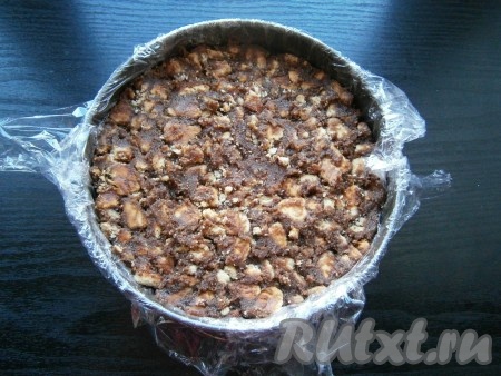 Разъемную форму диаметром 18-20 см застелить пищевой пленкой в 2 слоя, выложить массу из печенья, хорошо ее утрамбовать. Поместить в холодильник на 1-1,5 часа.
