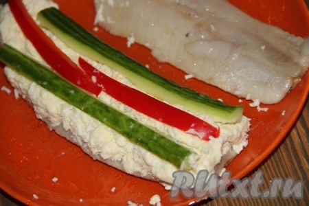Поверх начинки выложить брусочки огурца и болгарского перца и слегка вдавить.