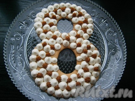 Таким же образом испечь и второй корж из оставшегося теста в виде этой же восьмерки. Коржи остудить. Поместить один корж на блюдо и разместить на нем крем (поместить в кулинарный мешок с круглой насадкой или насадкой "звездочка") в виде крупных капель. Между кремом, также, из кулинарного мешка нанести вареную сгущенку в виде капелек или звездочек.
