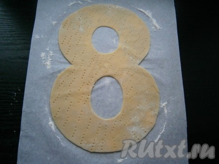 Ножом вырезать по шаблону восьмерку, наколоть тесто вилкой.
