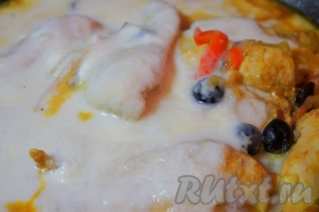 По истечении времени добавить к куриному филе и овощам сметану, хорошо перемешать и тушить под крышкой ещё 7-10 минут.
