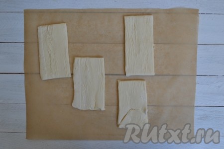 Предварительно разморозить слоеное тесто, для этого необходимо его просто оставить на столе, не снимая упаковку, на несколько часов. Можно разморозить тесто, оставив его с вечера в холодильнике, а утром его уже можно будет использовать. Затем аккуратно снять упаковку и расстелить тесто на пергаменте. Затем разрезать его на равные части (я разрезала на 4 части). От размера этих частей будет зависеть размер самих слоек. Чем меньше будет слойка, тем больше штучек получится в результате.