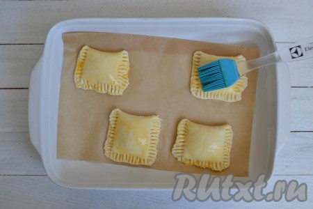 Вместе с пергаментом переложить слойки в форму для запекания. Смазать слоечки взбитым яйцом.
