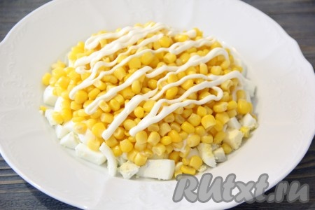 Яйца очистить, нарезать на средние кубики, выложить на плоскую тарелку и разровнять. Немного посолить и сделать тонкую решетку из майонеза. Кукурузу, слив лишнюю жидкость, выложить поверх яиц. Сделать решетку из майонеза.
