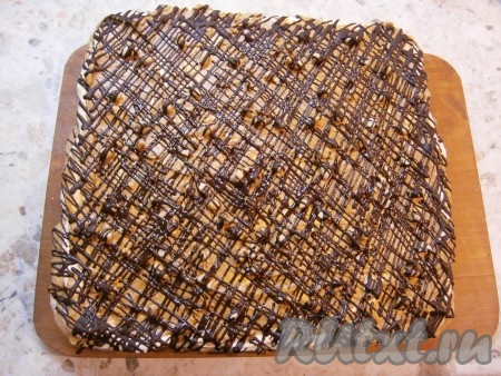 Коржи сложить друг на друга, немного придавить. Растопить на водяной бане шоколад, немного остудить и поместить его в кондитерский мешок. Обрезать кончик мешка и покрыть торт "Воздушный сникерс" хаотичными полосами или сеточкой из шоколада. Сразу же торт поместить в холодильник.