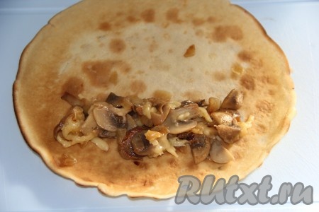 На каждый блин выложить часть сырно-грибной начинки и свернуть в плотную трубочку.