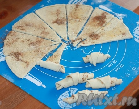 Начиная с большого края треугольничка, скатать рогалик, поплотнее прижимая тесто, чтобы при выпечке рогалик не развернулся.