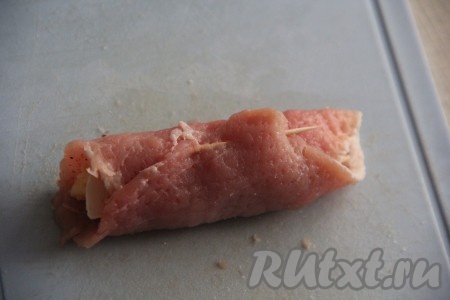 Свернуть каждый кусочек свинины с сырно-грибной начинкой в плотный рулет и скрепить конец рулетика зубочисткой.
