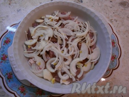 Очищенный лук нарезать тонкими полукольцами и выложить его поверх мяса.

