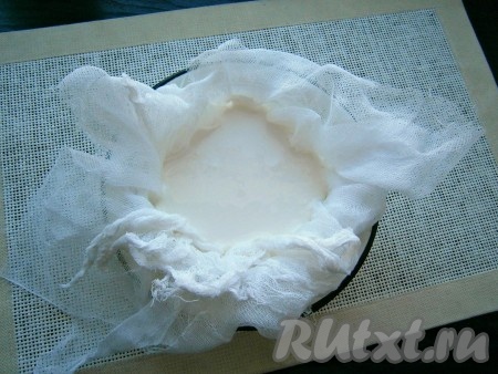 В специальную форму для сыра или пластиковое ведёрко с отверстиями на дне (отверстия нужны для того, чтобы через них сливалась сыворотка) поместить марлю, сложенную вчетверо. Вылить в неё смесь из кефира и сметаны.