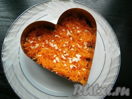Следующим слоем выложить натертую на средней терке очищенную сырую морковь, сверху - измельченный чеснок, чуточку этот слой посолить.
