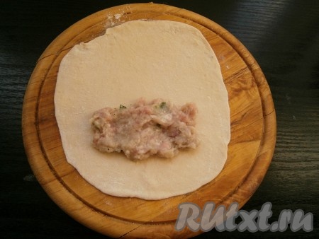 Тесто разделить на небольшие кусочки (по 50-60 грамм). Каждый кусочек теста раскатать в тонкую лепешку, подсыпая на стол немного муки. На край лепешки выкладывать по 1-2 столовых ложки фарша.
