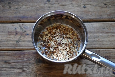 Пока тесто подходит, можно сделать ореховую начинку. Для приготовления начинки нужно молоко соединить с сахаром и отправить на огонь. Довести до кипения и проварить несколько минут, чтобы кристаллы сахара растворились. Ядра грецких орехов порубить ножом на мелкие кусочки и отправить в молоко. Перемешать и снять сотейник с огня, остудить.