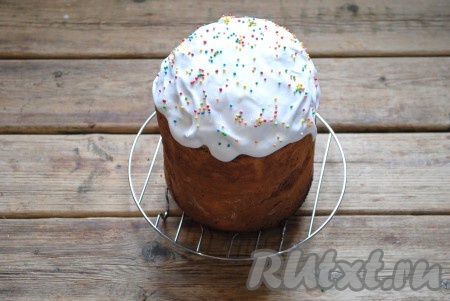 Когда кулич немного остынет, покрыть его белковой глазурью и украсить кондитерской посыпкой. Для приготовления глазури нужно взбить яичный белок миксером в лёгкую пену. Затем небольшими порциями добавлять сахарную пудру, не прекращая взбивание. Когда масса станет плотной и блестящей - глазурь готова.