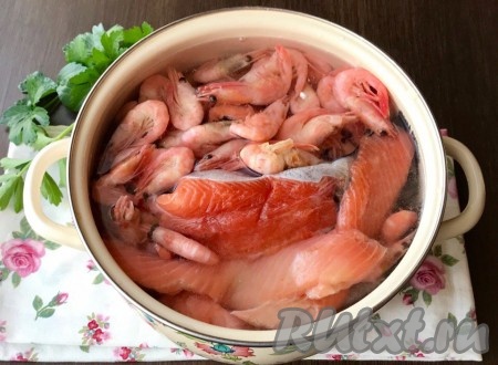 Промоем красную рыбу и креветки, зальем холодной водой и поставим на средний огонь.
