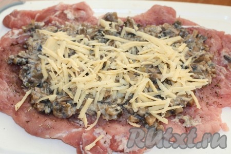 Выложить на мясо грибы с луком, распределить по всему куску, не доходя до краев по 1,5 см. Сверху посыпать натёртым сыром.
