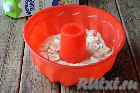 Половину теста вылить в форму для выпечки (силиконовую форму можно не смазывать маслом и не застилать пергаментом). Очищенные бананы нарезать на кружочки и выложить поверх теста.