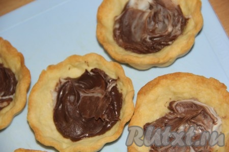 Выложить на дно испеченных корзинок шоколадную пасту. Я использовала шоколадно-молочную пасту "Несквик". Для моих пирожных ушло по 1 чайной ложке с горкой шоколадной пасты.
