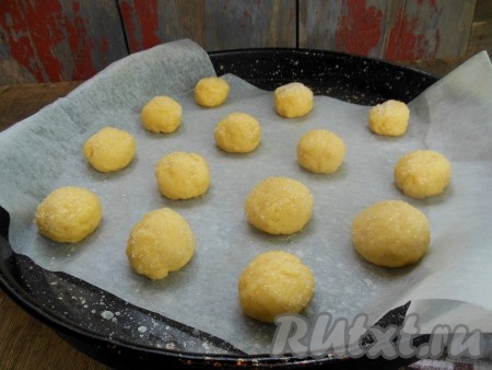 На противень, застеленный пергаментом, выложите печенье так, чтобы сторона, посыпанная сахаром, была сверху. Шарики выкладывайте на небольшом расстоянии друг от друга, прижимать ладошкой их не надо.
