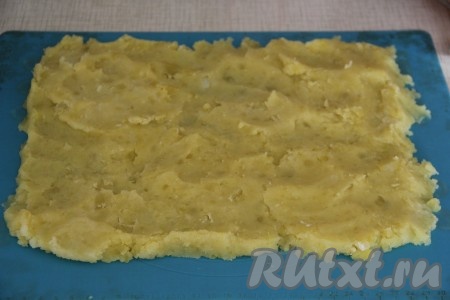 Картофельное пюре выложить на силиконовый коврик и разровнять ровным слоем в прямоугольный пласт. Если нет силиконового коврика, то можете воспользоваться пекарской бумагой. Небольшое количество пюре не выкладывайте на коврик, а отложите в сторону (этим пюре мы будем в дальнейшем украшать рулет).
