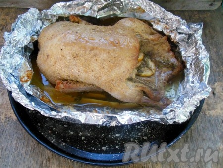 Запекайте утку, полностью завернутую в фольгу, в заранее разогретой духовке при температуре 150-160 градусов 2 часа. По истечении времени достаньте утку из духовки. На фото видно, что из утки в процессе запекания выделилось много сока и жира, которые остались в форме из фольги.
