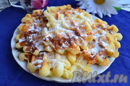 Аккуратно деревянной лопаткой переложить творожные вафли с панелей вафельницы на решётку, немного остудить и переложить на тарелку. Постепенно испечь все вафельки, давая им немного остыть на решётке. Вкуснейшие, мягкие, нежные венские вафли, приготовленные с добавлением творога в электровафельнице, подавать в тёплом виде со сметаной. Их также просто можно посыпать сахарной пудрой.