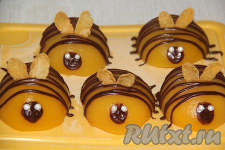 Можно украсить торт по своему желанию, я сделала пчёлок из персиков. Получилось ярко! Для приготовления "пчёлок", дольки консервированных персиков нужно обсушить. Затем растопить шоколад и поместить его в кондитерский мешок. Сделать тонкие полоски из шоколада на персиках. Затем из шоколада нарисовать кружок, глазки сделать из сахарных бусинок. Крылышки сделать из кукурузных хлопьев.
