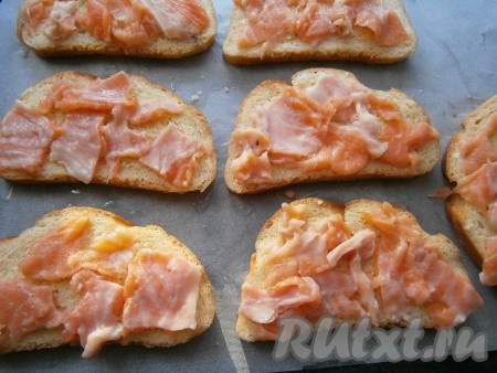 Застелить противень пергаментом, смазать его растительным маслом. Выложить на противень все ломти батона так, чтобы сторона хлеба, смоченная в молочно-яичной смеси, была сверху. На ломти выложить тоненькие кусочки рыбы.
