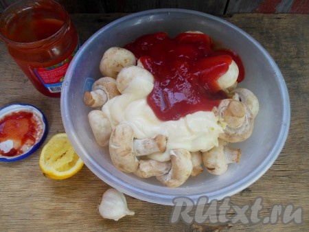 Шампиньоны тщательно вымойте, дайте стечь воде. Переложите грибы в глубокую миску, добавьте мелко нарезанный чеснок, черный молотый перец и соль по вкусу, майонез и томатный соус, полейте соком, выжатым из лимона, аккуратно перемешайте.