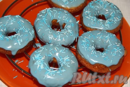 Обмакнуть пончики с одной стороны в глазурь и выложить на решетку, сразу посыпать кондитерской посыпкой, пока глазурь не застыла.

