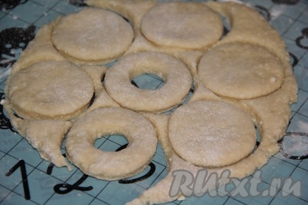 Раскатать тесто на припыленной мукой поверхности. Вырезать пончики с помощью тонкого стакана, серединку вырезать пробкой от пластиковой бутылки.
