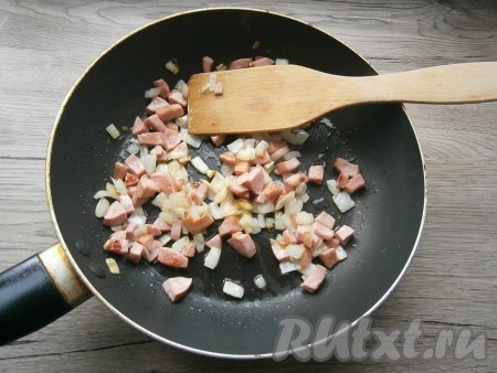Обжарить, помешивая, до мягкости лука и легкой румяности колбасы, остудить.
