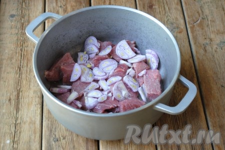 В казан или толстостенную кастрюлю выложить кусочки говядины, сверху разложить лук и влить воду.&nbsp;
