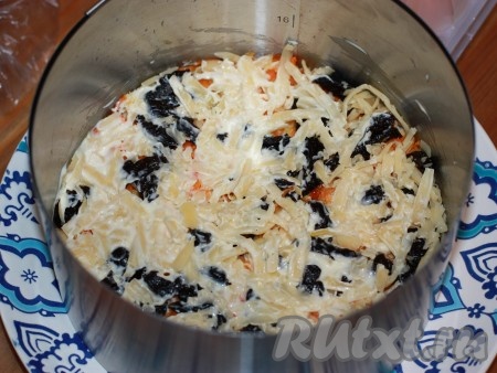 Сыр натереть на крупной терке, выложить слоем на чернослив, добавить вторую часть чеснока и смазать майонезом.