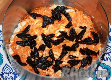 Чернослив промыть, залить на несколько минут горячей водой, дать постоять, затем воду слить и нарезать его соломкой. Выложить сверху на морковь.