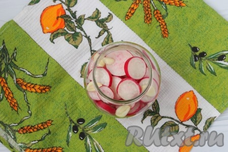 Нарезанную редиску сложить в чистую банку, перекладывая чесноком.
