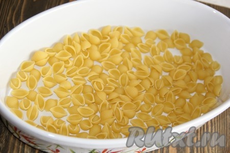 На дно жаропрочной формы выложить часть сухих макарон.
