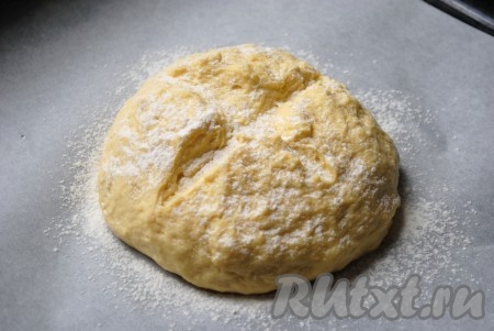 Из теста сформировать круглую заготовку, на которой острым ножом сделать крестообразный надрез. Выложить колобок на противень, застеленный пергаментом, притрусить мукой. Оставить тесто на 5-10 минут, прикрыв полотенцем.
